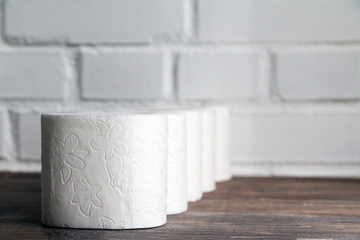 Toilet paper row on wooden table. Copy space. Selective focus.