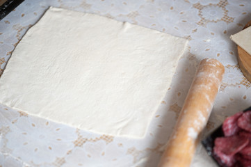 On the table the flour of the hand of the cook roll out the dough, the ingredients.