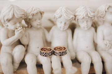 Wedding rings of the bride and groom are on a figurines in the form of small angels, which stands on a stone base