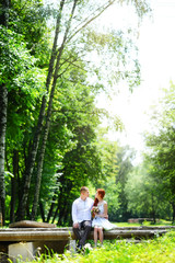 Groom fixes his blue bow tie standing before the bride on old stone bridge