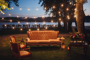 Wedding. In the forest on the river bank there is sofa and armchair, next to it there is wooden...