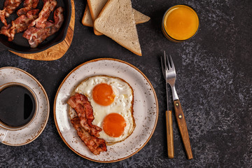 Breakfast with bacon , fried egg, coffee and orange juice.