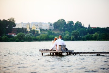 Fototapeta na wymiar Beautiful young wedding couple, bride and groom posing on lake background. The groom and the bride on pier