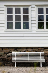 Fototapeta na wymiar Symmetrical white bench in front traditional house.