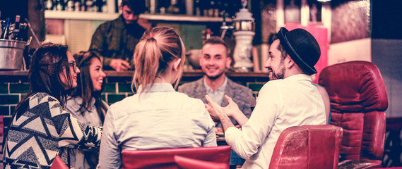 Group of young trendy friends chatting and laughing together inside cocktail fashion bar - obrazy, fototapety, plakaty