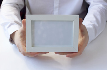 White photo frame in hands.