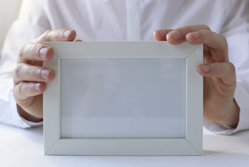 White photo frame in hands.