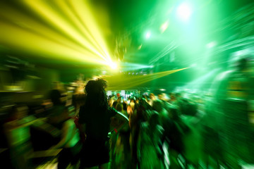 Young people dancing in night disco club with color laser lights in background