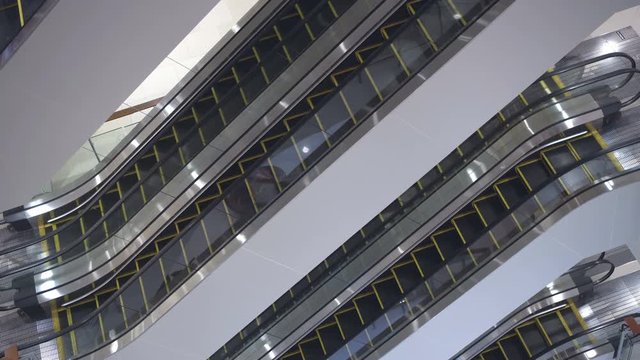 Inside view of empty shopping mall. Escalators moving staircases in motion no people