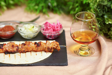 Shashlik kebab skewer on slate plate, sauce, onions and cognac