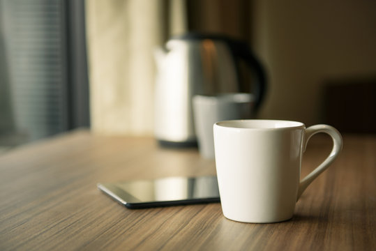 Digital tablet and cup of coffee on wooden desk. Selective focus.