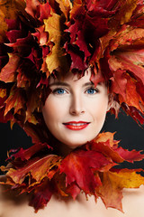 Fototapeta premium Autumn Beauty. Beautiful Woman with Fall Maple Leaves Wreath and Fashion Makeup