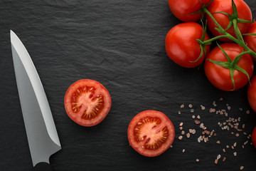 High angle view of freshly picked, juisy tomatoes on dark stone background with copy space