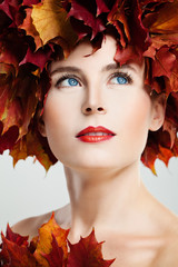 Autumn Portrait of Beautiful Woman with Red Fall Maple Leaves Wreath and Perfect Makeup