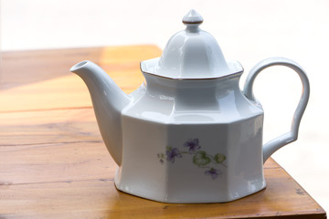 Vintage white ceramic teapot on wood  table.