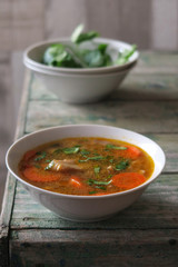 Soup with oyster mushrooms in white bowl on wooden desk.