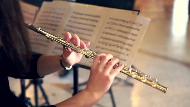 Woman Musician Plays the Flute. Flutist Professionally Playing the Flute in the Orchestra, Classic Music
