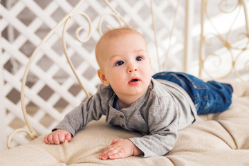 Adorable baby boy in sunny bedroom. Newborn child relaxing. Nursery for young children.Family morning at home. Little kid lying on tummy