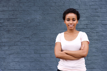 smiling african young woman in t shirt standing by gray wall