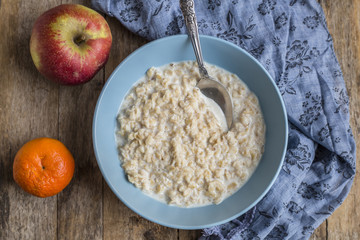 Oatmeal porridge in bowl for breakfast on rustic wooden table