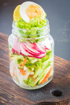 Various vegetables and egg in a glass jar on wooden table. Vegetable mix and chicken slices  in a glass jar on wooden table. clean eating. Healthy denner.
