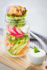 Vegetable salad and egg  in a glass jar yogurt sauce  on wooden table. Clean eating. Healthy denner.