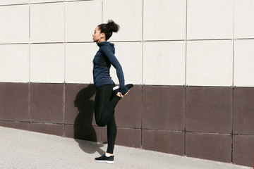 Woman stretching her legs before a run on a city street