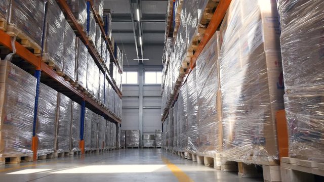 Shelves, racks of boxes inside a storage warehouse. Forklift driving on a background. 4K.