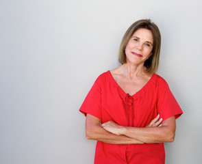 beautiful older woman with arms crossed against gray background