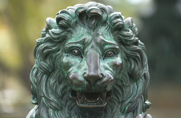 Front view of a bronze sculpture of a royal lion with the paws on a ball with the three crowns