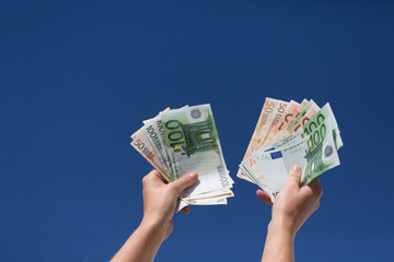 hands with euro notes in the blue sky 