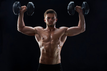 Fototapeta na wymiar Horizontal shot of a sporty young shirtless man exercising with heavy dumbbells on black background fitness gym confidence masculinity lifestyle bodybuilding shaping toning ripped abs abdominal torso.