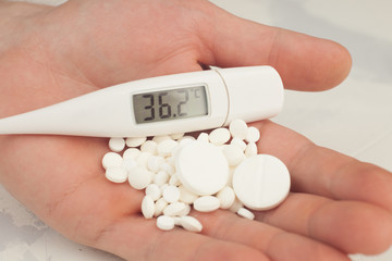 health care, traditional medicine and flu concept - pills and thermometer. Medical pills and...