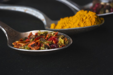 spoons with salt and spices on black chalkboard