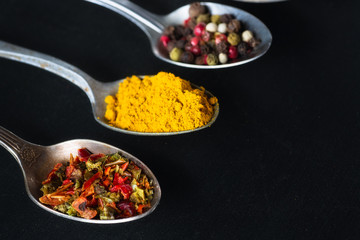 spoons with salt and spices on black chalkboard