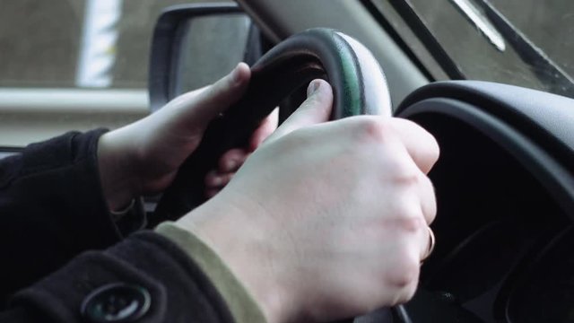 Driver's hands on the steering wheel closeup. Highway and urban traffic and driving scene.