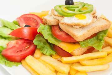 club sandwich on a white plate with french fries and vegetables