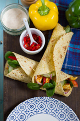 Fajitas with chicken and vegetables. Fajitas, tortillas, wraps on wooden board. Blue background and vegetables. 