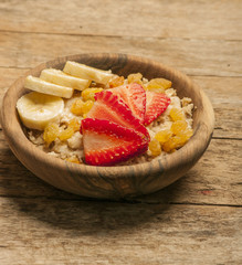 oatmeal porridge with strawberry and banana in wood bowl