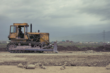 The bulldozer of yellow color in the field