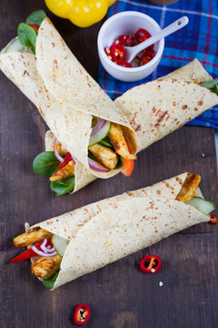 Fajitas with chicken and vegetables. Fajitas, tortillas, wraps on wooden board. Blue background and vegetables. 