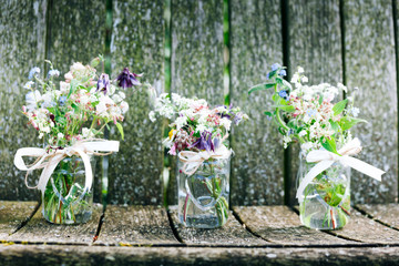 Flower bouquets in glass jars on rustic wood background, summer, flowers, bride, bridesmaid