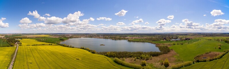 Aerial view panorama of colorful agricultural fields with a lake under blue sky in germany