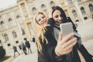 Two beautiful young women making selfie in the city