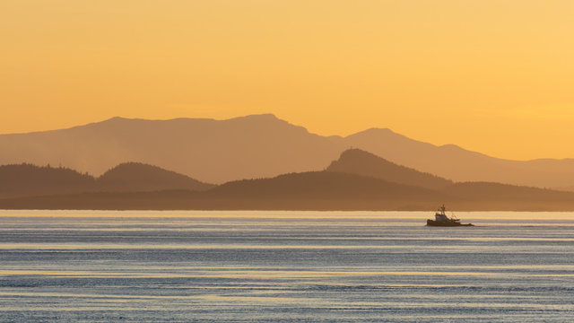 View of tugboat moving on sea with mountains in background at sunset