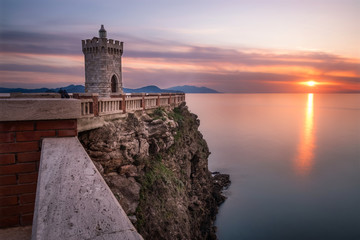 Sunset over the sea in Piombino. Small lighthouse, landmark in Tuscany, Italy.