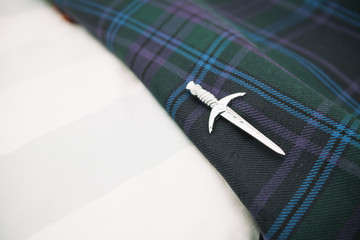 Scottish wedding kilt pin on tartan background, prop