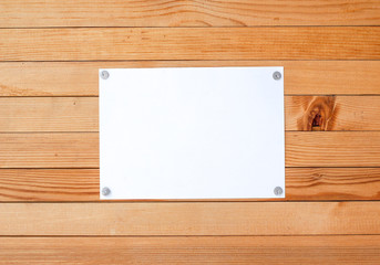 Empty paper ad loose leaves on a wooden wall. Attached metal buttons. Blank advertisement with cut slips