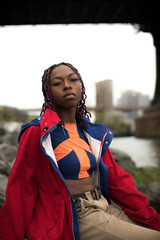 A candid portrait of an attractive, young, black woman sitting on the shore of New york City's East...
