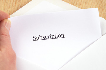 Subscription printed on white paper and envelope, hand holding it, wooden background